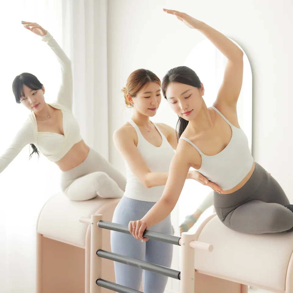 바렐 수업에서 강사가 손으로 자세를 교정해 주는 모습