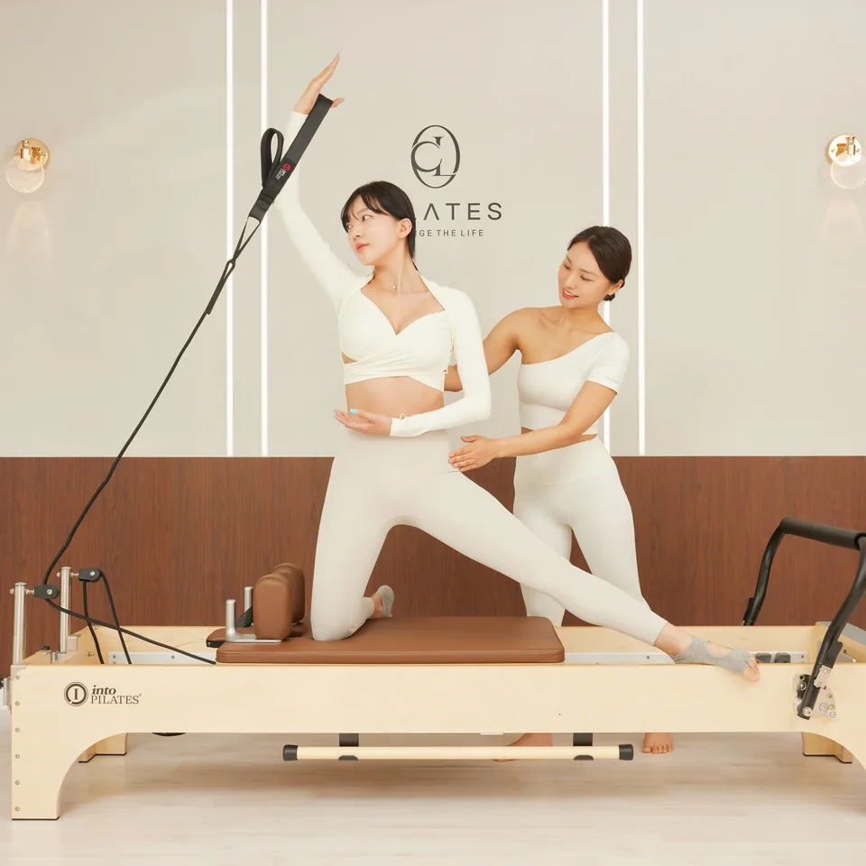 리포머 수업에서 강사가 회원의 자세를 잡아주는 모습